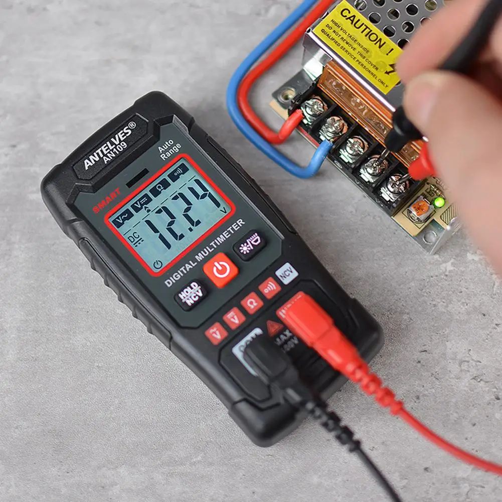 Digital multimeter being used to measure voltage on a battery pack with a hand holding a probe.