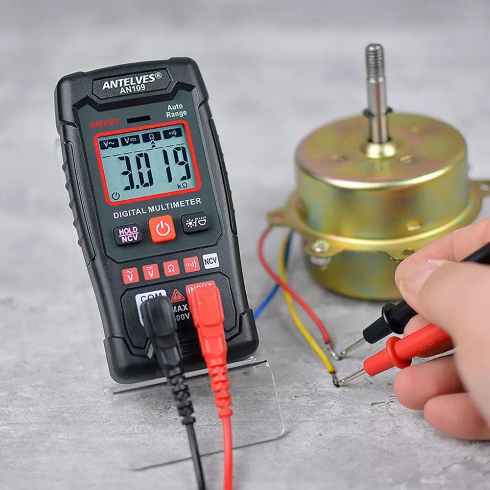 Digital multimeter being used to measure electrical components on a gray surface